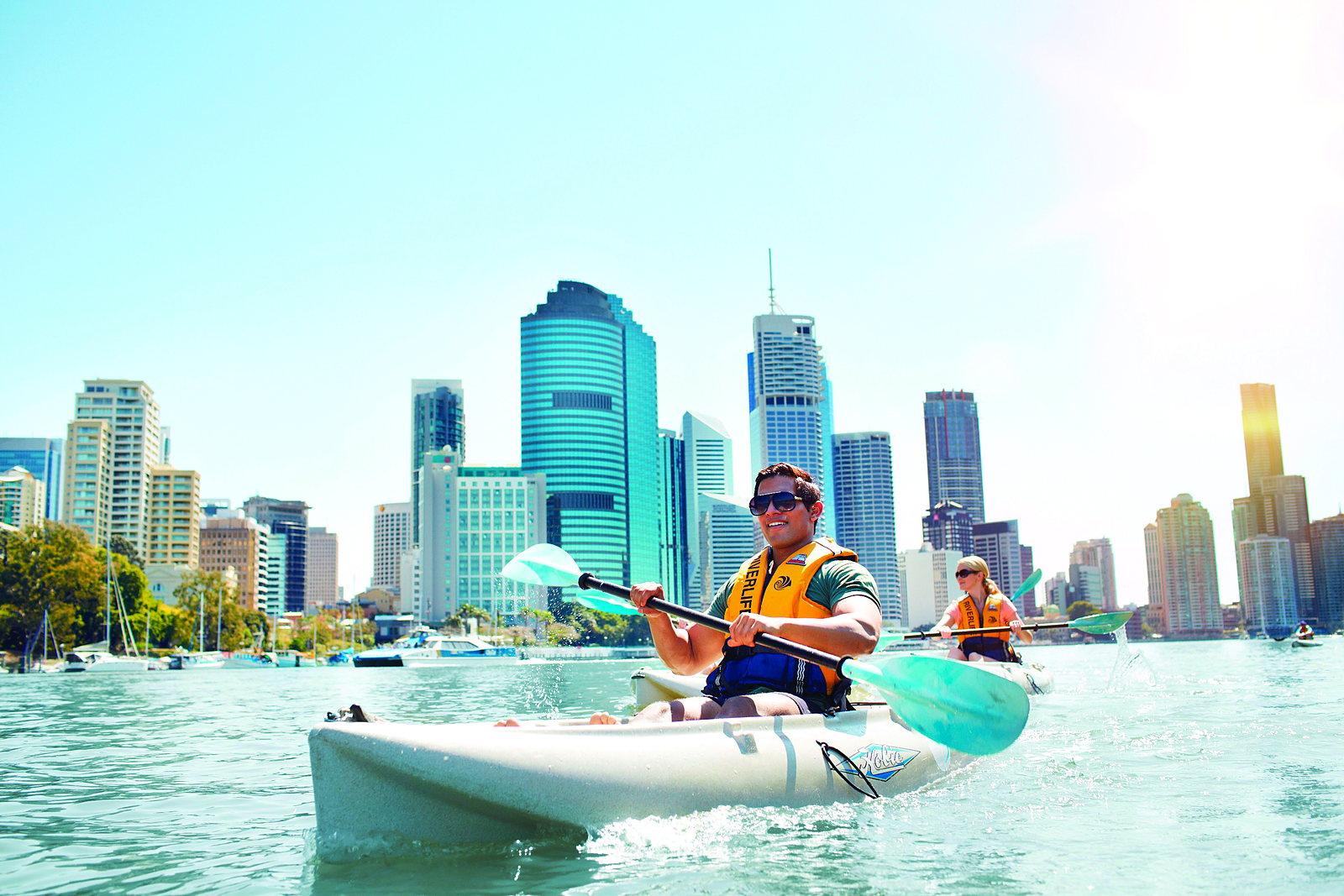 Kayaking on the Brisbane River with the city skyline in the background on a sunny day
